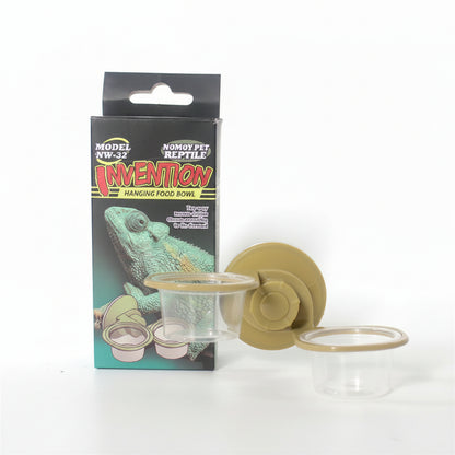 NOMOY PET Invention Hanging Food Bowl for reptiles and amphibians, shown with its retail packaging box, a tan suction cup, and two clear plastic food bowls on a white background.