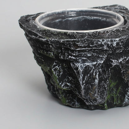 A close-up of a black and gray rock-textured planter pot with a circular opening, shown against a plain white background.