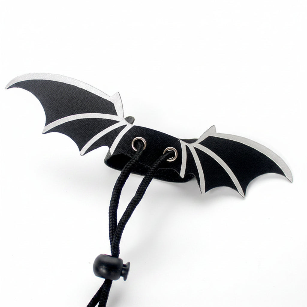 A black bat-shaped accessory with silver-toned edges and a black cord hanging from the center, shown on a plain white background.
