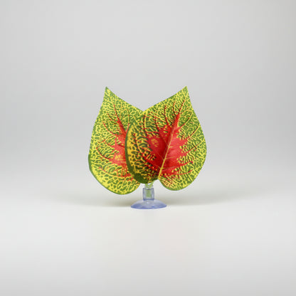 Three artificial decorative leaves with green, yellow, and red variegated patterns on a clear stand, shown on a white background with the brand name NOMOY PET in the top left corner.